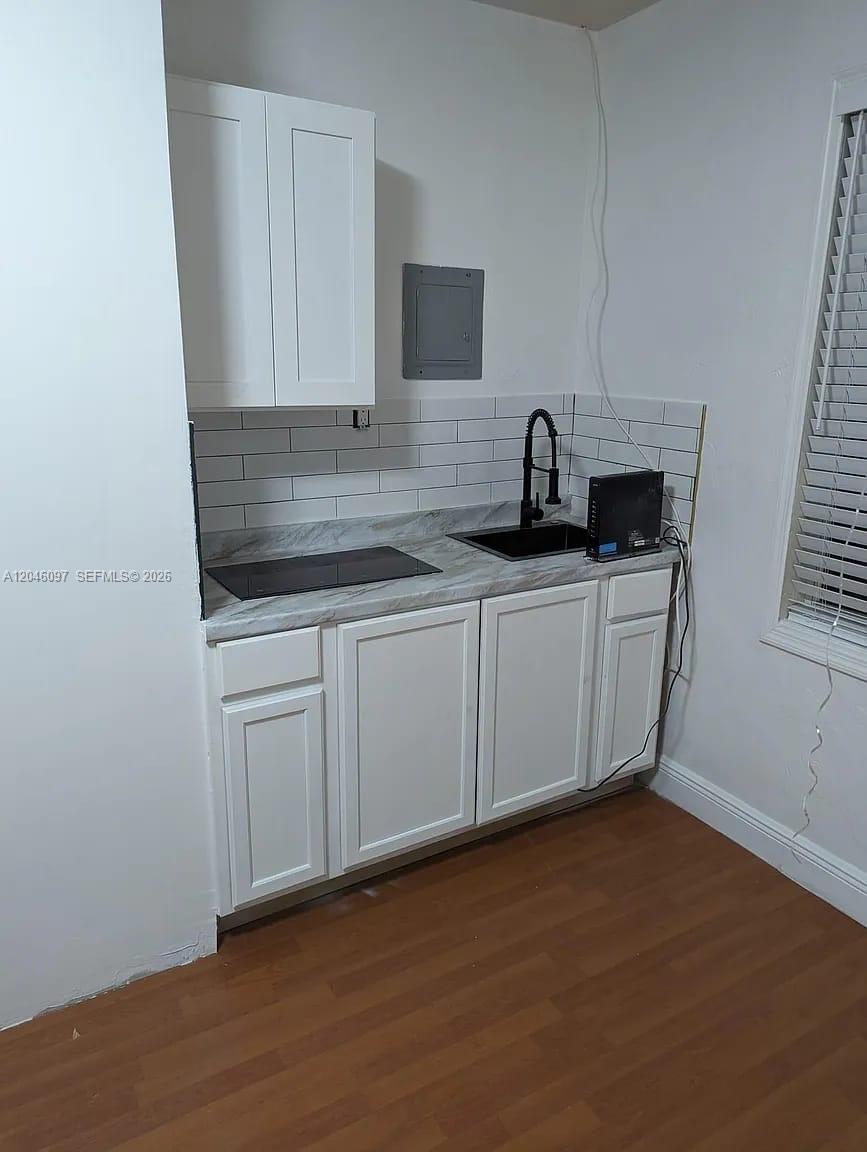 A small kitchenette features white cabinets, a marble-look countertop, a sink, and a cooktop — 435 SW 33rd Ave, Miami FL 33135, MIAMI, FL