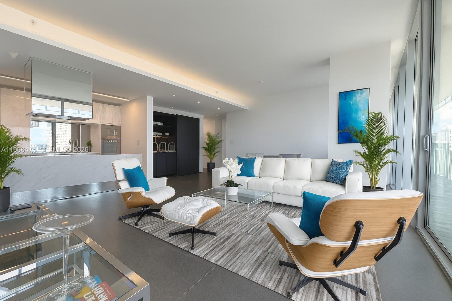 A modern living room features white sofas, two lounge chairs, and a kitchen in the background — 120 Ocean Dr # 700, Miami Beach FL 33139, MIAMI BEACH, FL