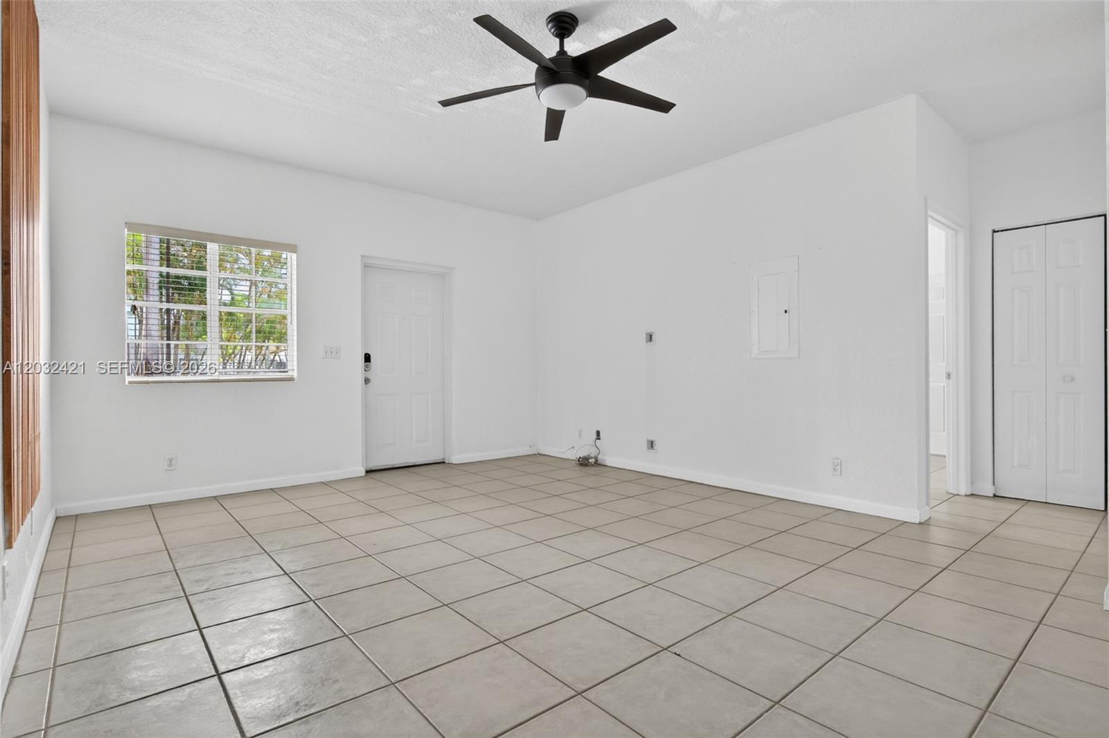 An empty room with white walls, beige tile flooring, a ceiling fan, and a window — 4902 Washington St # 4, Hollywood FL 33021, HOLLYWOOD, FL