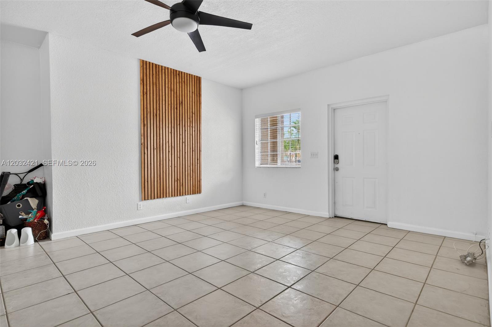 A room with white walls, tile flooring, a wood slat accent wall, and a ceiling fan — 4902 Washington St # 4, Hollywood FL 33021, HOLLYWOOD, FL