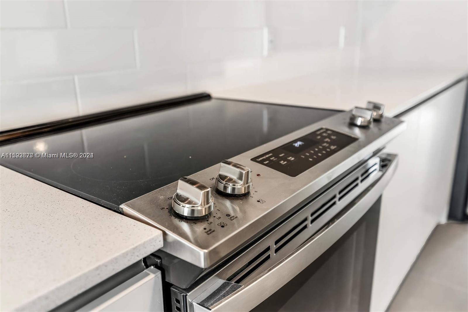 A stainless steel electric range is set into a white countertop in a modern kitchen — 2561 NE 193rd St # 1103, Miami FL 33180, MIAMI, FL