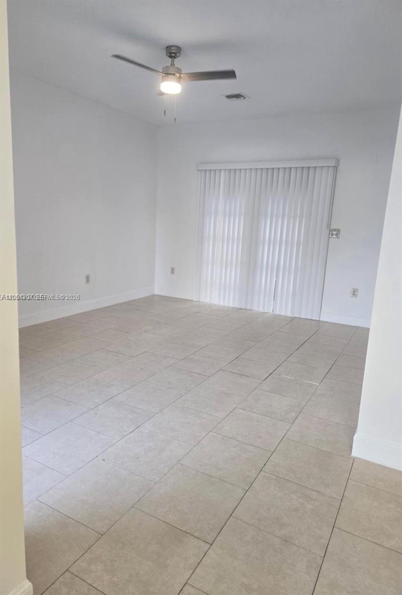An empty room features light-colored tile flooring, white walls, and a sliding glass door — 9740 NW 5th Ave # B, Miami FL 33150, MIAMI, FL