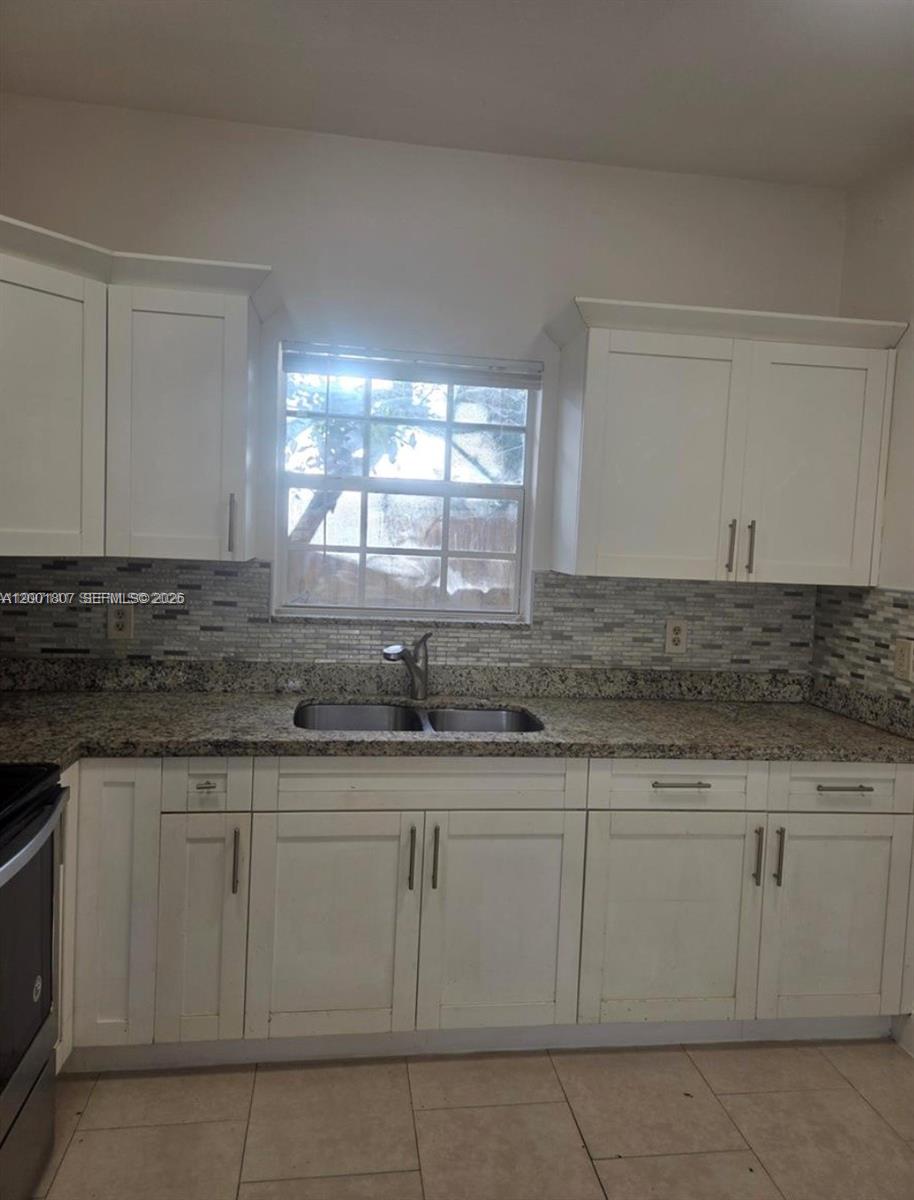 A kitchen features white cabinets, granite countertops, a double sink, and a tiled backsplash — 9740 NW 5th Ave # B, Miami FL 33150, MIAMI, FL