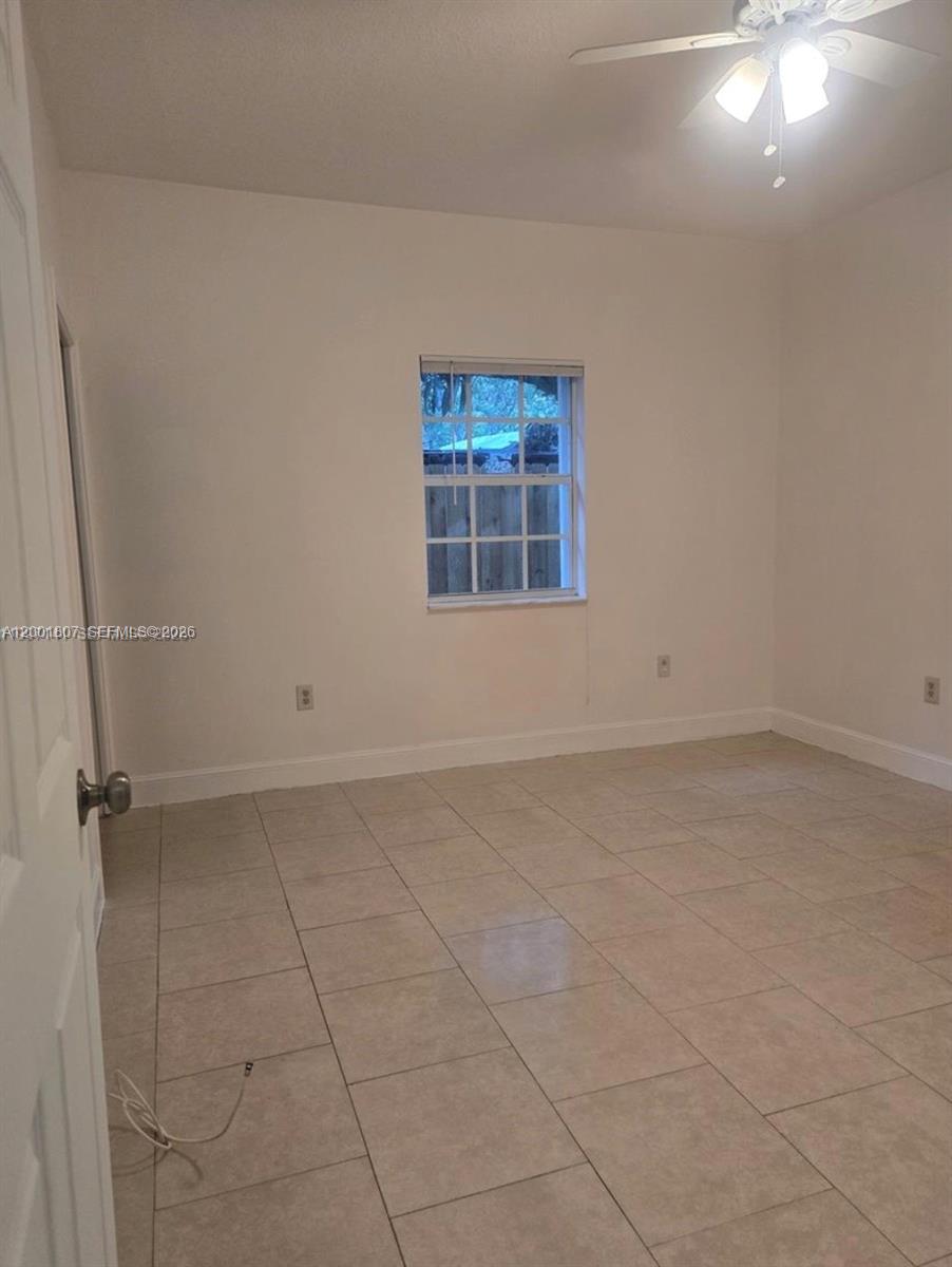 An empty bedroom features light-colored tile flooring, white walls, and a ceiling fan — 9740 NW 5th Ave # B, Miami FL 33150, MIAMI, FL