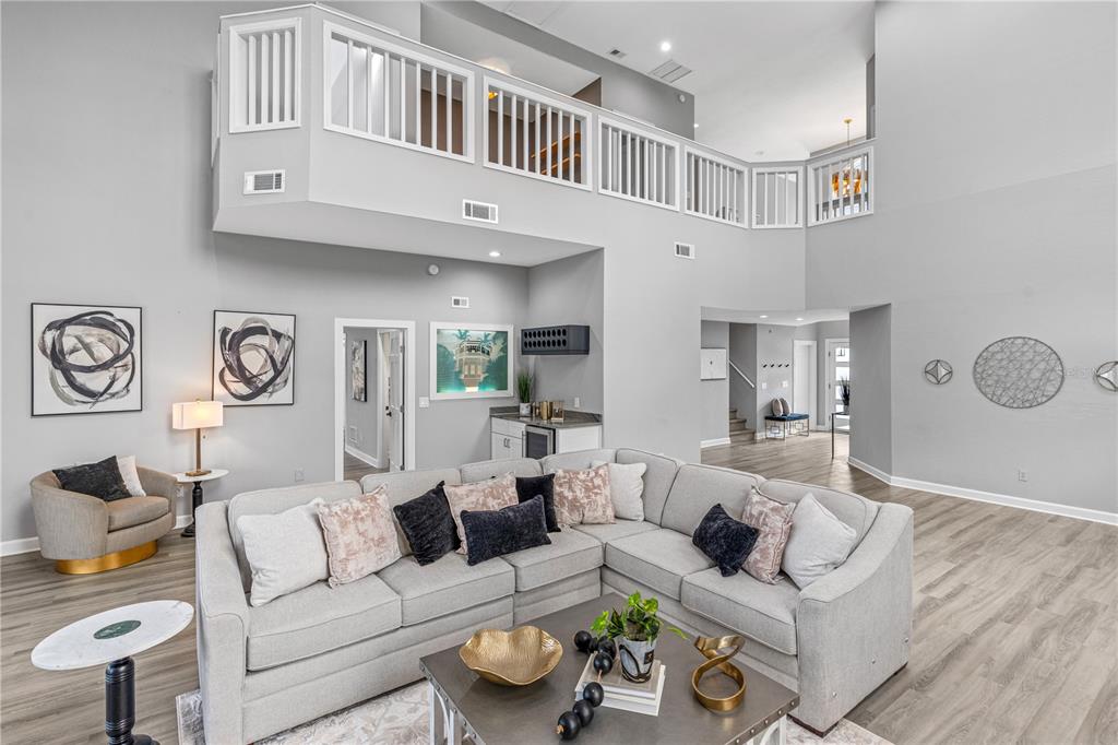 A spacious living room features a large sectional sofa, a wet bar, and a lofted balcony — 57 BAY POINTE DRIVE, ORMOND BEACH, FL