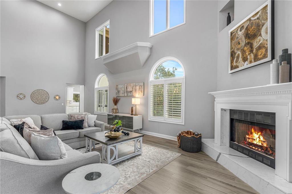 A living room features a high ceiling, a fireplace, and light-colored wood flooring — 57 BAY POINTE DRIVE, ORMOND BEACH, FL