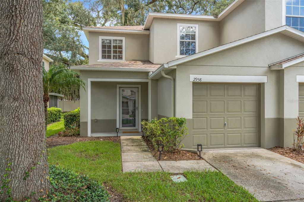 A two-story townhouse with a beige stucco exterior, a single-car garage, and a front walkway — 2958 ROYAL TUSCAN LANE, VALRICO, FL