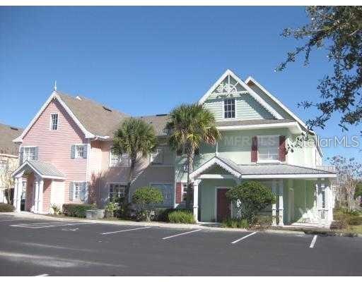 A two-story building with pink and light green siding features multiple gabled roof sections — 5006 MANGROVE ALLEY UNIT 205, KISSIMMEE, FL