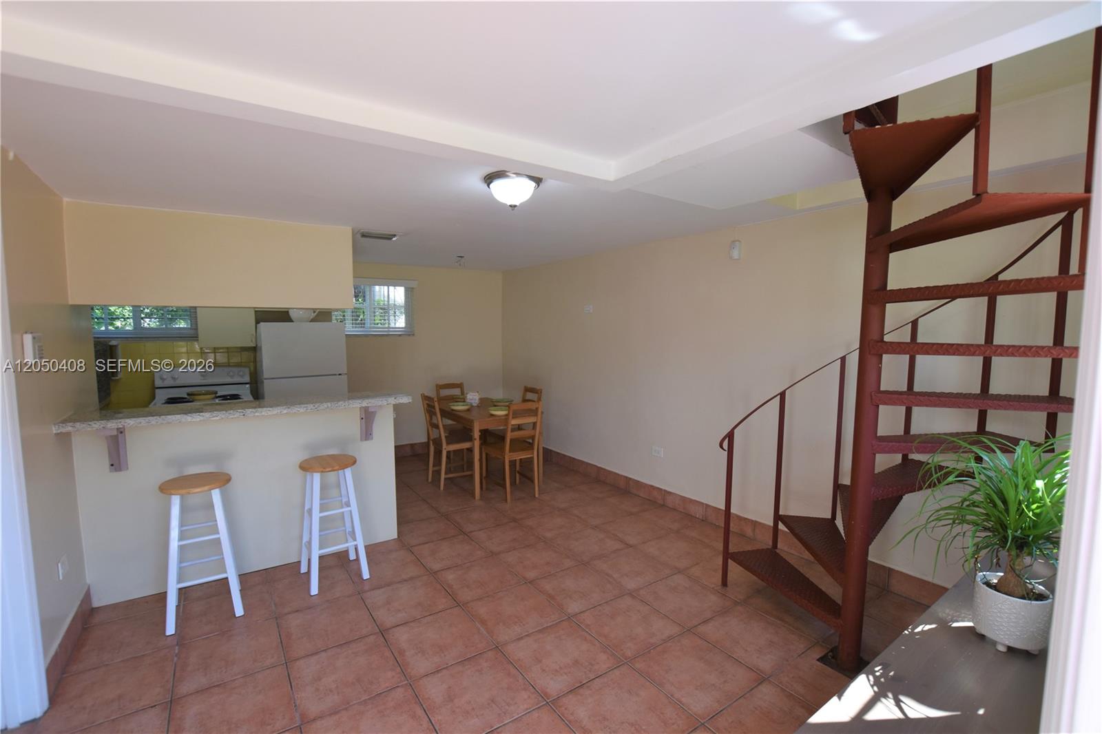 An open-plan kitchen and dining area features tile flooring and a red spiral staircase — 2615 SW 20th St, Miami FL 33145, MIAMI, FL