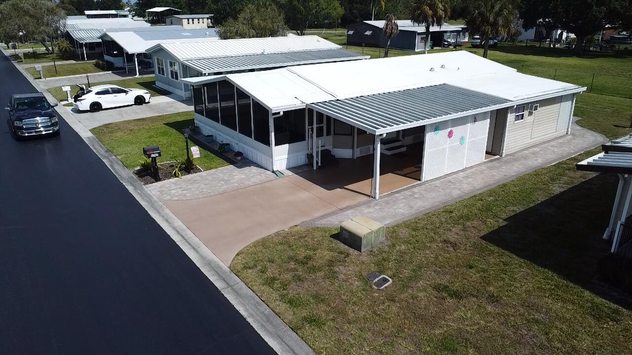 An aerial view of a mobile home with a carport, screened porch, and paved driveway — 1747 SW 35th Circle, Okeechobee FL 34974, OKEECHOBEE, FL