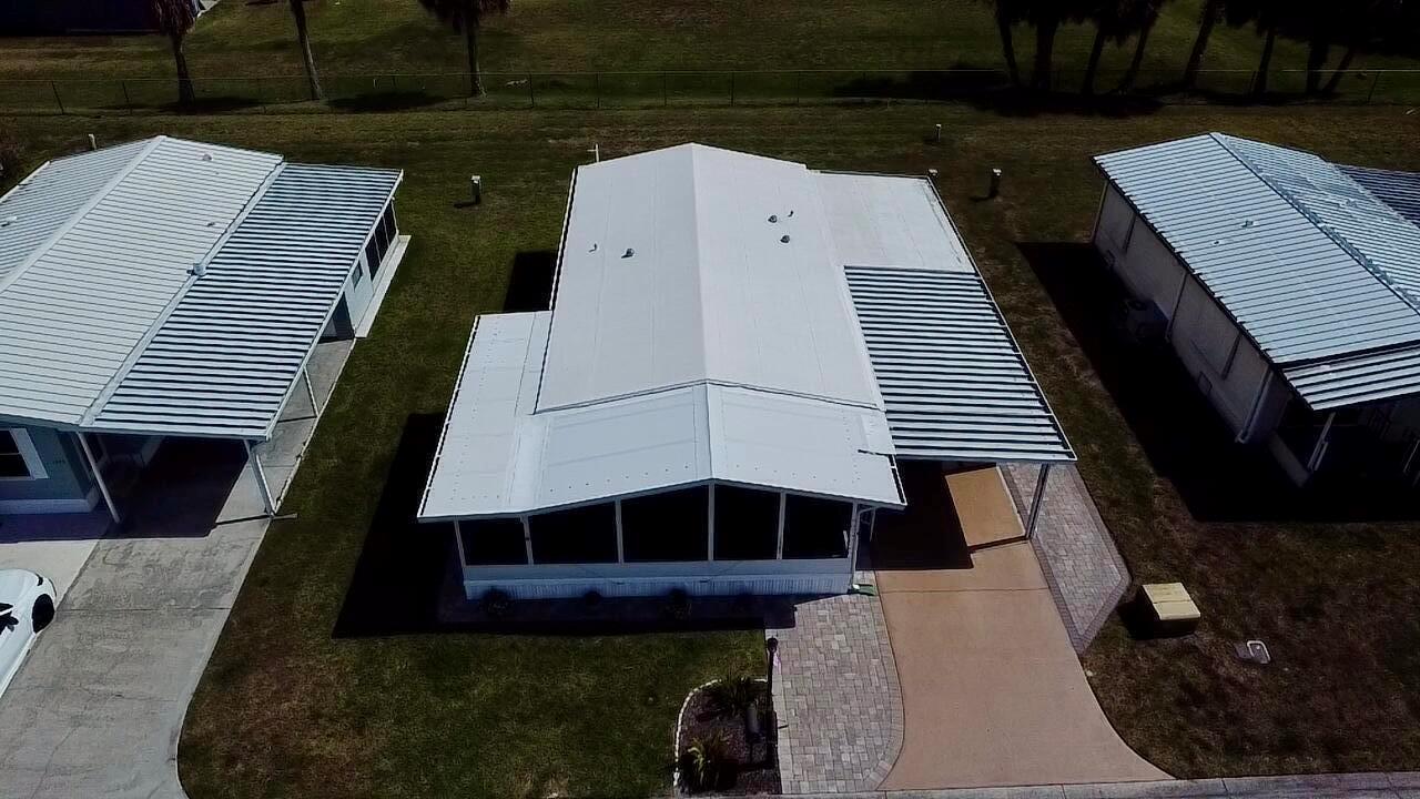 An aerial view shows the white metal roofs of three manufactured homes with paved driveways — 1747 SW 35th Circle, Okeechobee FL 34974, OKEECHOBEE, FL