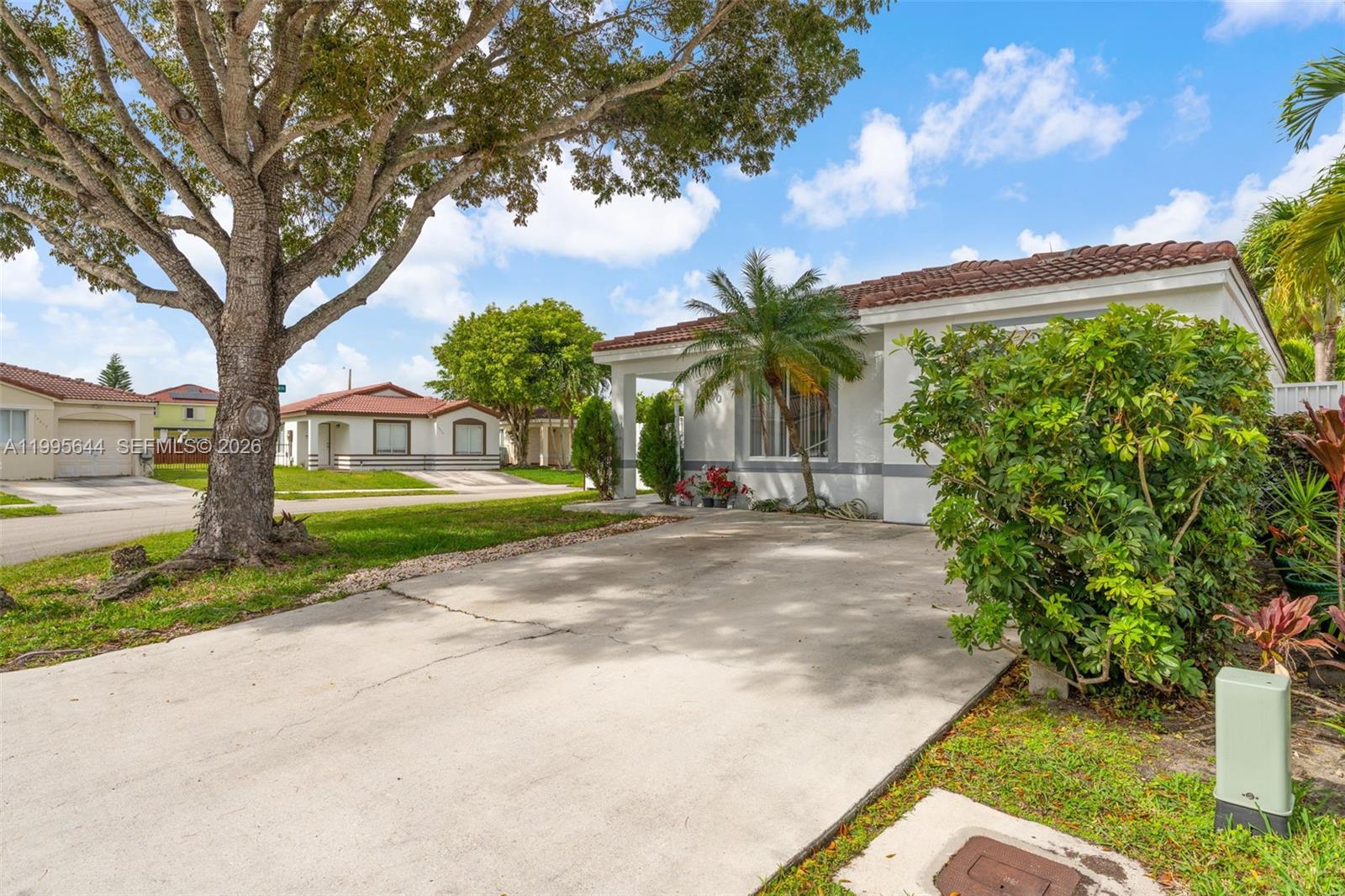 A single-story house with a concrete driveway, a large tree, and a tiled roof — 17570 SW 142nd Ct, Miami FL 33177, MIAMI, FL