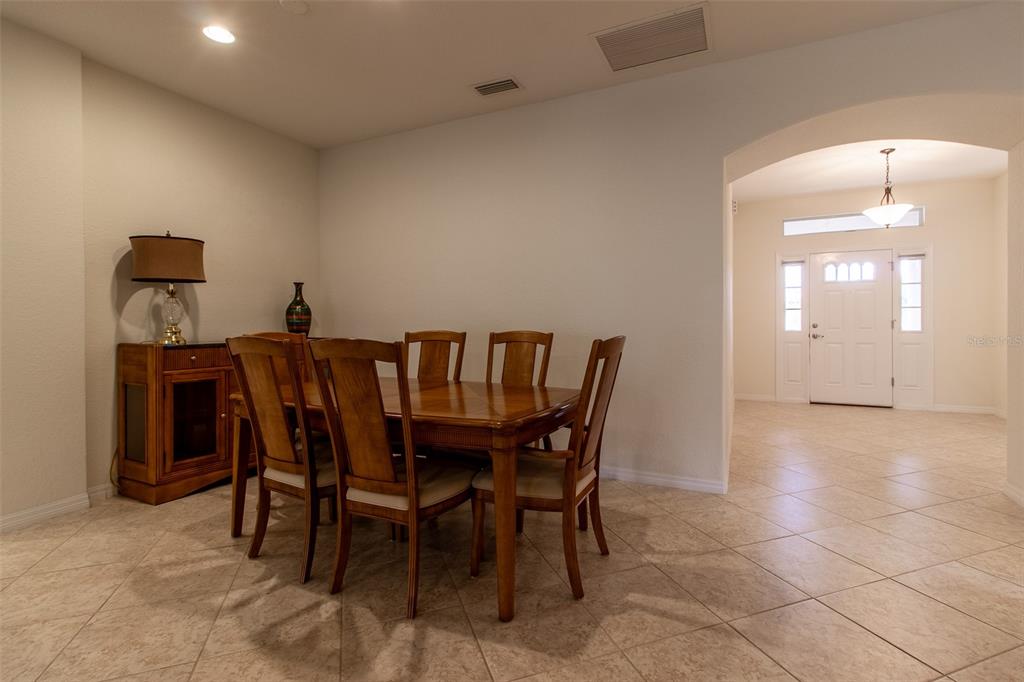 A dining room with a wooden table and chairs sits adjacent to a tiled entryway — 16205 SW 12TH TERRACE, OCALA, FL