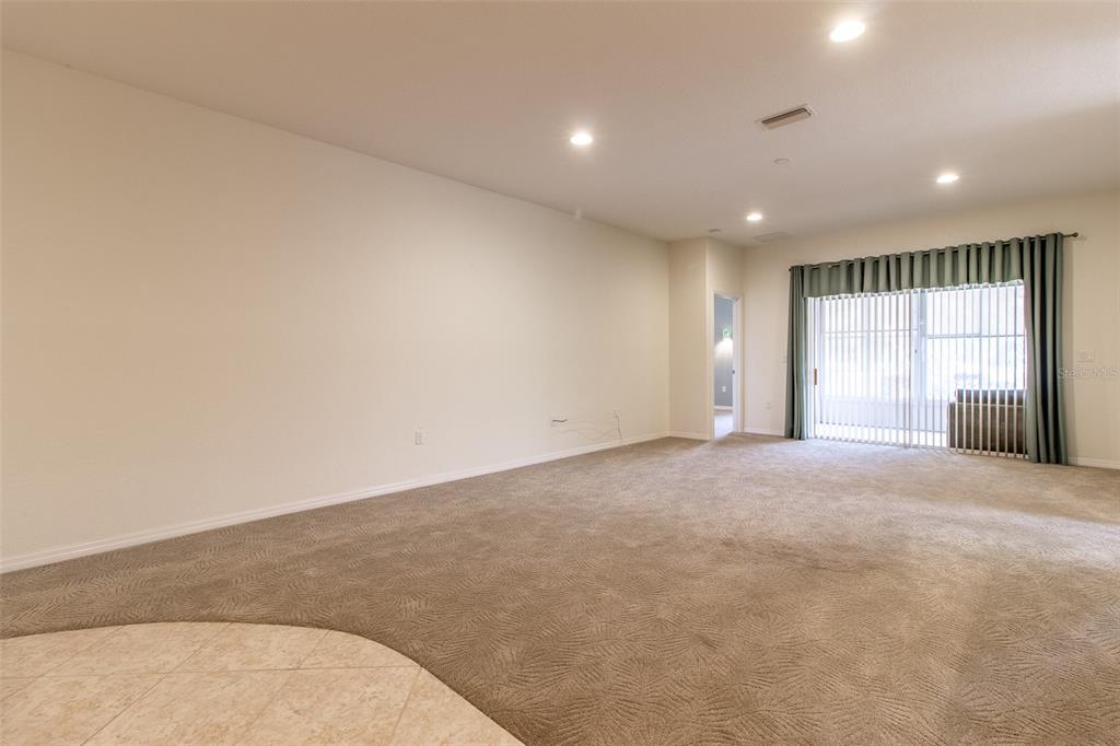 A spacious living room features beige carpeting, neutral walls, recessed lighting, and sliding glass doors — 16205 SW 12TH TERRACE, OCALA, FL