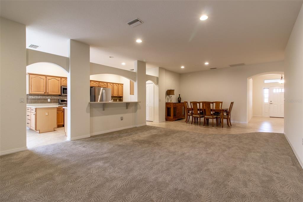 A carpeted living area opens to a dining room and a kitchen with wooden cabinets — 16205 SW 12TH TERRACE, OCALA, FL