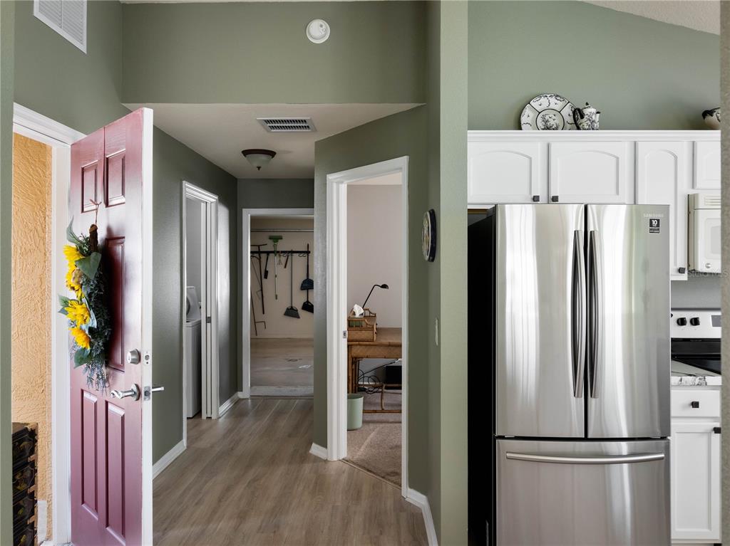 A hallway with wood-look flooring leads to a garage and office, adjacent to a kitchen — 2453 VIOLET COURT, THE VILLAGES, FL