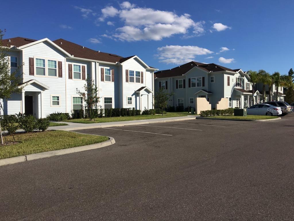 Exterior view of multi-story apartment buildings with light siding and a paved parking lot — 3225 CUPID PLACE, KISSIMMEE, FL
