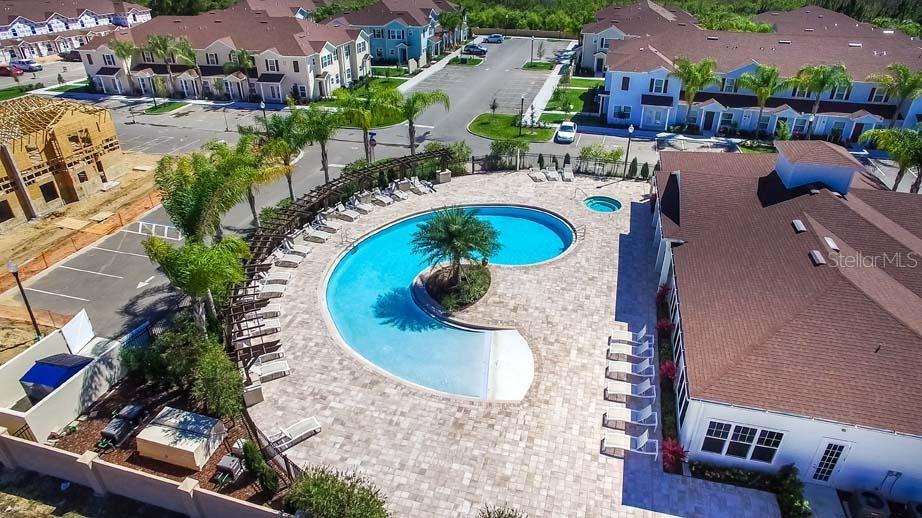 An aerial view shows a curved swimming pool and hot tub surrounded by a patio — 3225 CUPID PLACE, KISSIMMEE, FL