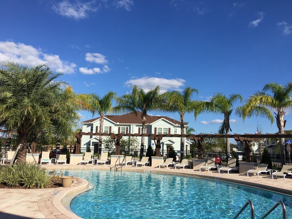 A swimming pool with lounge chairs and a pergola sits in front of a house — 3225 CUPID PLACE, KISSIMMEE, FL
