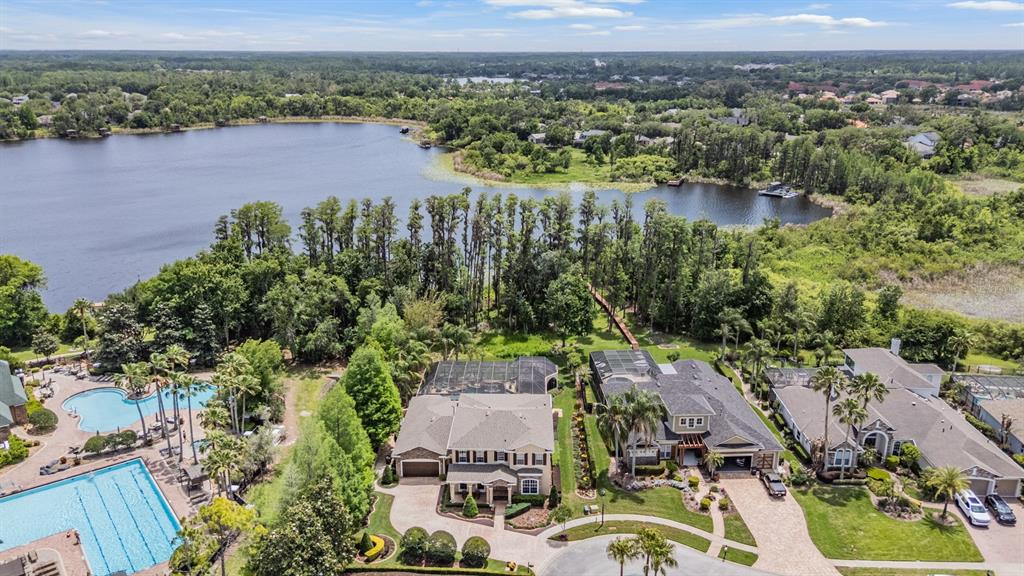 An aerial view shows houses with screened pools near a lake and community swimming pools — 21246 QUIET HAVEN COURT, LAND O LAKES, FL
