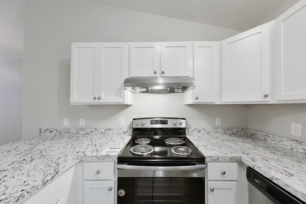A kitchen features white cabinets, granite countertops, and a black electric range with a hood — 6771 SW 149TH LANE ROAD, OCALA, FL