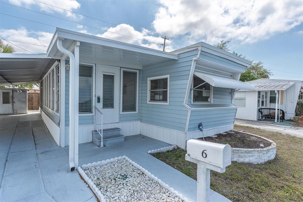 A light blue mobile home with a carport and a white mailbox in the front yard — 7801 34TH AVENUE N UNIT 6, ST PETERSBURG, FL