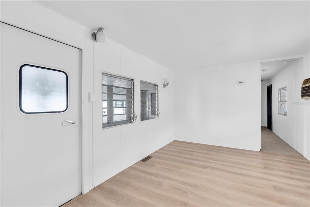 An interior room with white walls, light wood-look flooring, two windows, and a door — 7801 34TH AVENUE N UNIT 6, ST PETERSBURG, FL