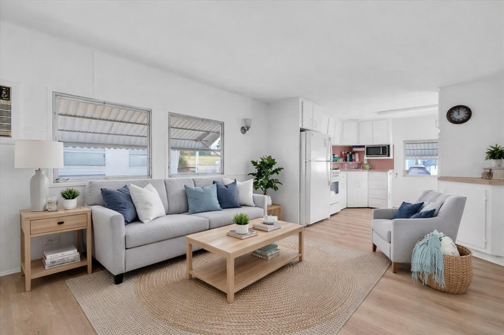 A living room with a grey sofa, armchair, light wood coffee table, and an open kitchen — 7801 34TH AVENUE N UNIT 6, ST PETERSBURG, FL