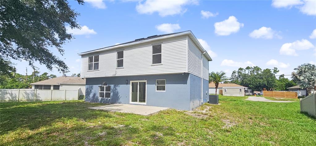 The exterior of a two-story house features light blue stucco, white siding, and a concrete patio — 4948 CROMEY ROAD, NORTH PORT, FL
