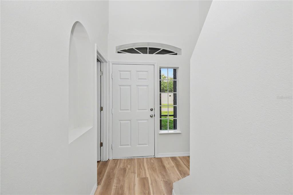 A bright entryway features a white front door, a side window, and light wood flooring — 4948 CROMEY ROAD, NORTH PORT, FL