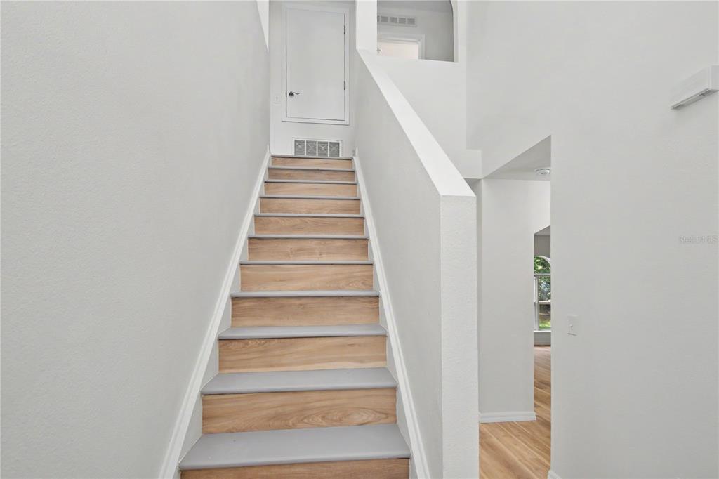 A staircase with wood-look treads and gray risers leads to a landing with a door — 4948 CROMEY ROAD, NORTH PORT, FL