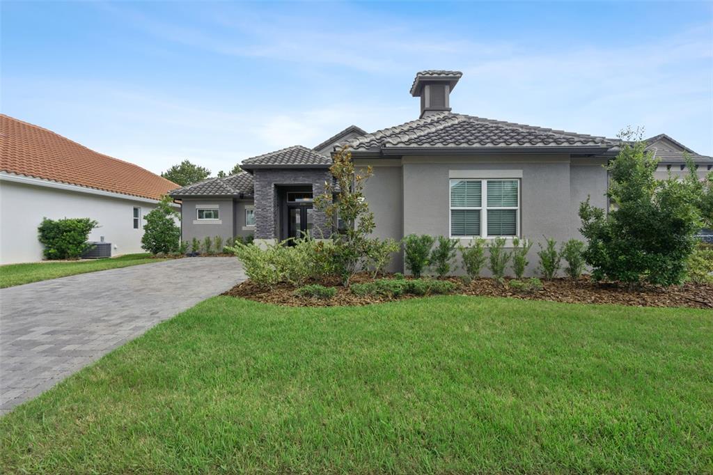 A gray single-story house with a tiled roof, stone accents, and a paved driveway — 2730 WILLINGAM DRIVE, DAVENPORT, FL