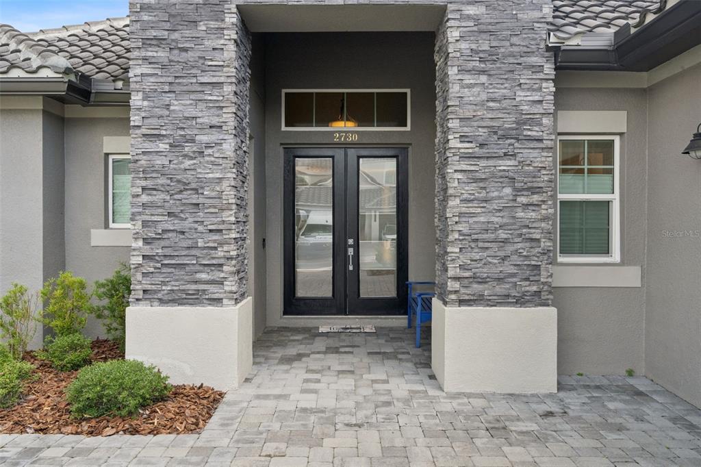 The front entrance features a stone-clad porch with double glass doors and a paved walkway — 2730 WILLINGAM DRIVE, DAVENPORT, FL