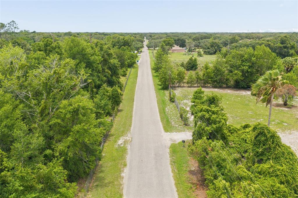 An aerial view shows a paved road stretching through a rural area with surrounding trees — 9361 ORCHARD WAY, SPRING HILL, FL