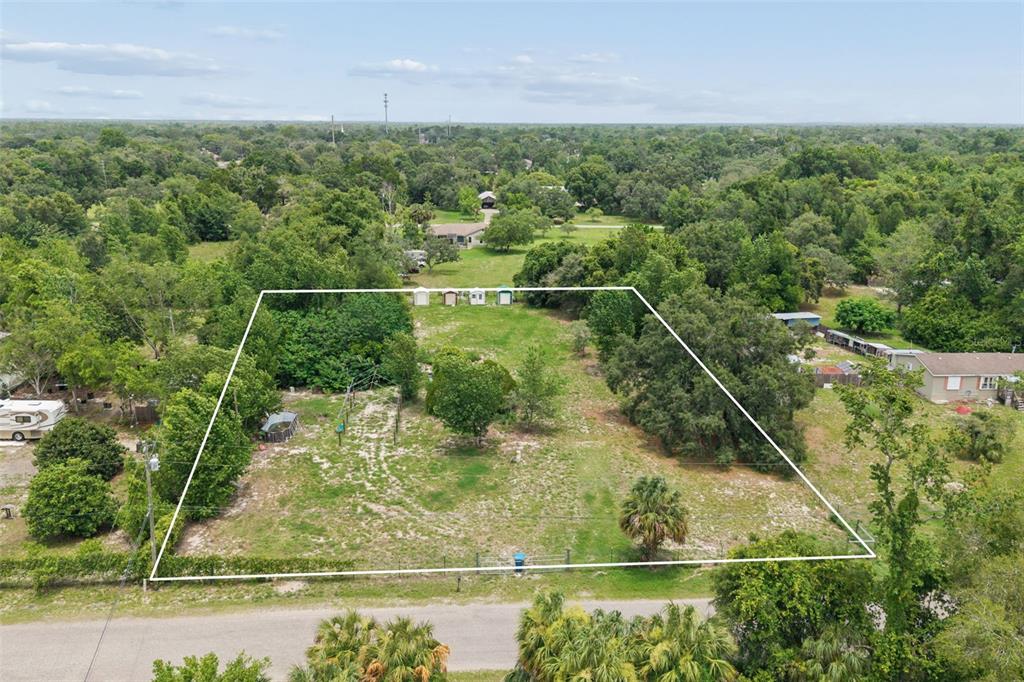 An aerial view shows a rectangular, fenced-in grassy lot with several trees and small sheds — 9361 ORCHARD WAY, SPRING HILL, FL
