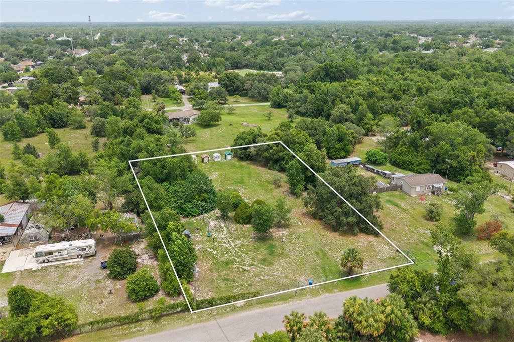An aerial view shows a rectangular plot of land outlined in white near a road — 9361 ORCHARD WAY, SPRING HILL, FL
