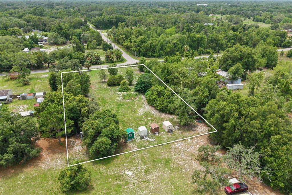 An aerial view shows a rectangular plot of land with four small sheds and trees — 9361 ORCHARD WAY, SPRING HILL, FL