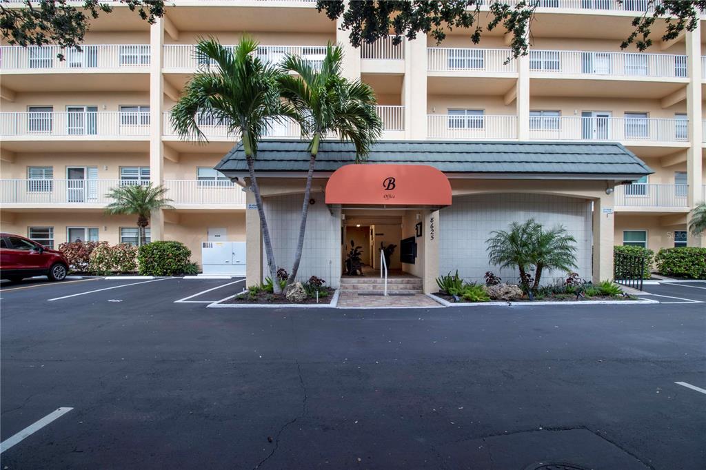 The exterior of a multi-story apartment building features a covered entrance marked with a B — 8625 MIDNIGHT PASS ROAD UNIT B508, SARASOTA, FL