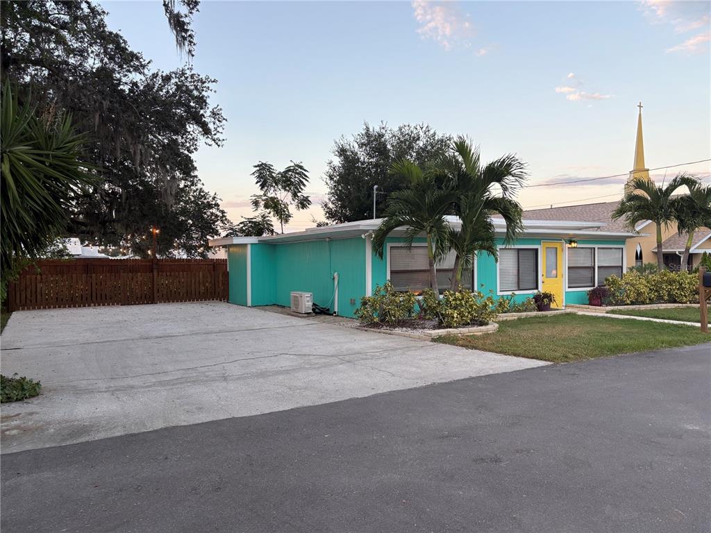 A paved patio features two red umbrellas, outdoor furniture, and string lights at night — 839 3RD STREET N, SAFETY HARBOR, FL