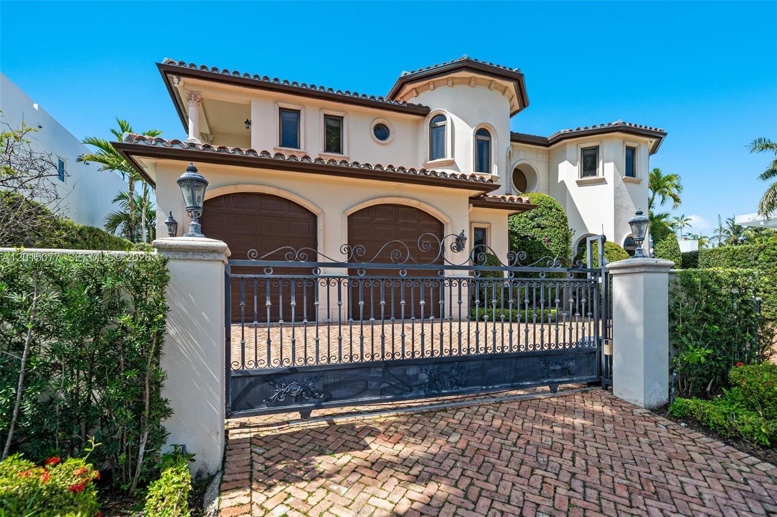 A two-story Mediterranean-style house features a gated driveway, arched garage doors, and a tiled roof — 1251 99th St, Bay Harbor Islands FL 33154, BAY HARBOR ISLANDS, FL