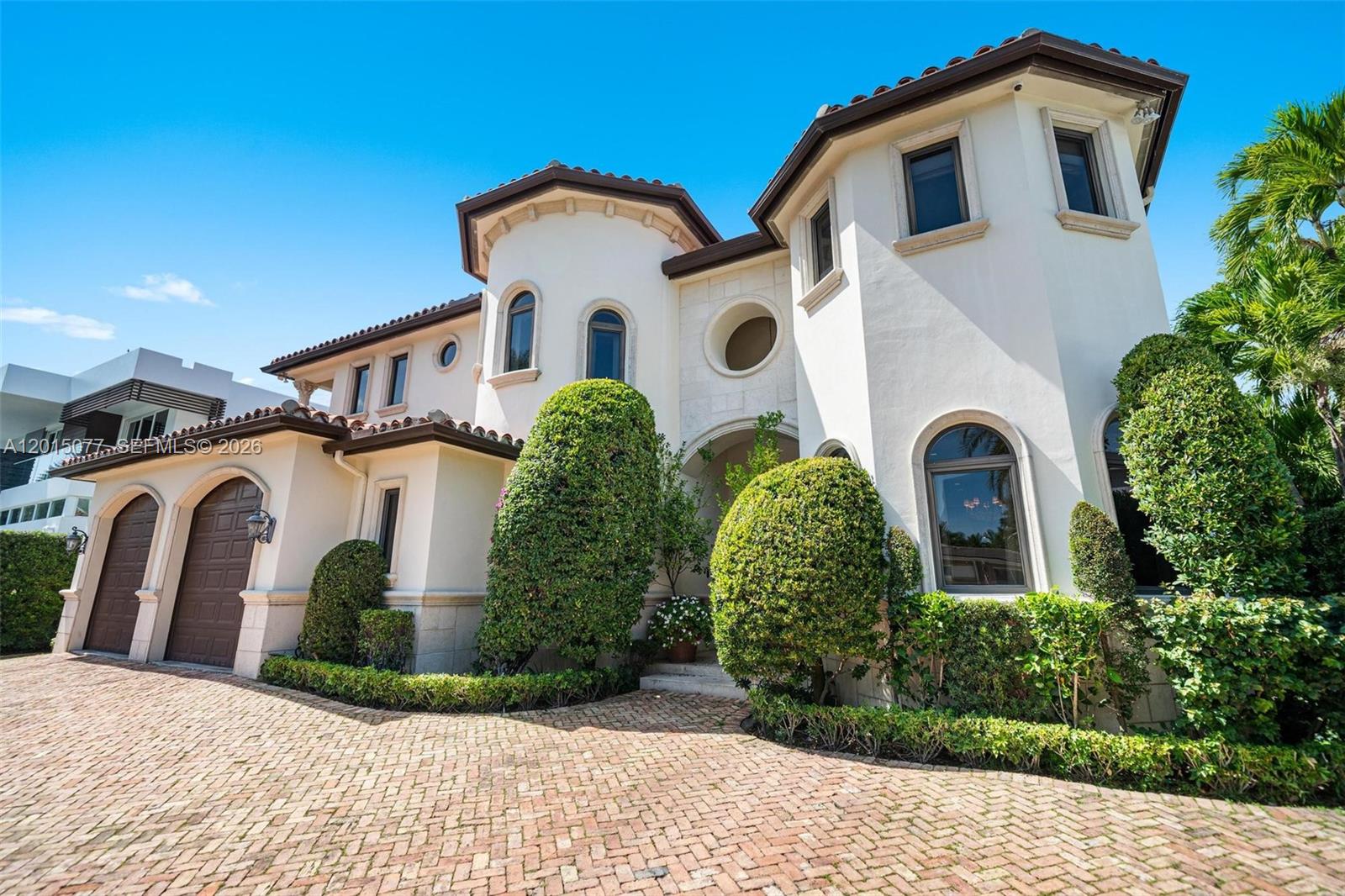 A two-story Mediterranean-style house features a brick driveway, arched windows, and manicured landscaping — 1251 99th St, Bay Harbor Islands FL 33154, BAY HARBOR ISLANDS, FL