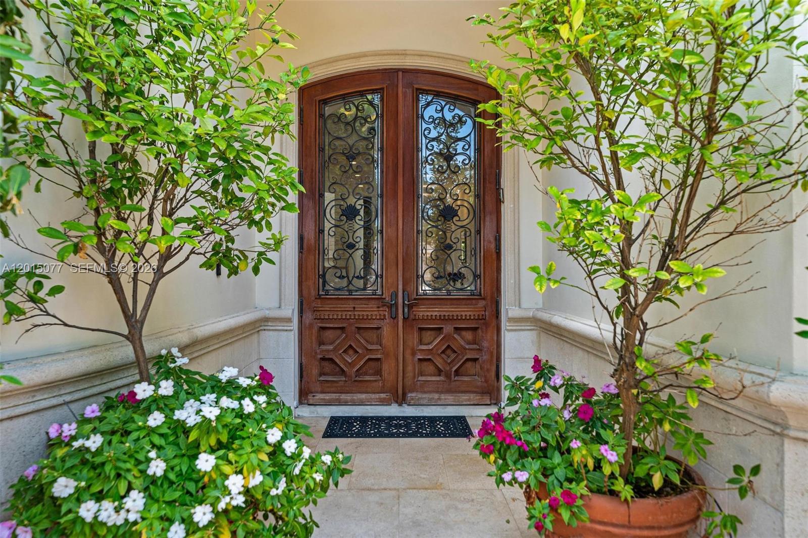 A pair of wooden arched double doors with iron grilles sits between two potted trees — 1251 99th St, Bay Harbor Islands FL 33154, BAY HARBOR ISLANDS, FL