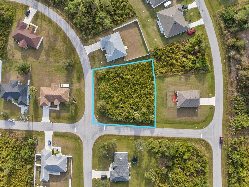 An aerial view shows a vacant, wooded residential lot outlined in blue within a neighborhood — 12142 APPLEBERG CIRCLE, PORT CHARLOTTE, FL