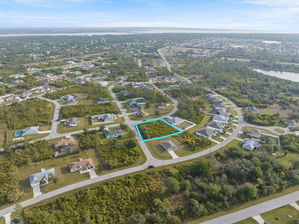 An aerial view shows a vacant, rectangular residential lot outlined in blue within a neighborhood — 12142 APPLEBERG CIRCLE, PORT CHARLOTTE, FL