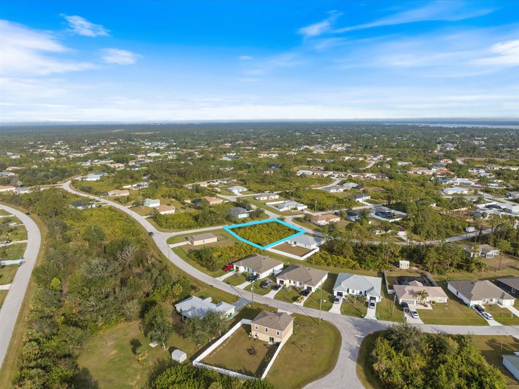An aerial view shows a vacant, rectangular residential lot highlighted in blue among suburban houses — 12142 APPLEBERG CIRCLE, PORT CHARLOTTE, FL