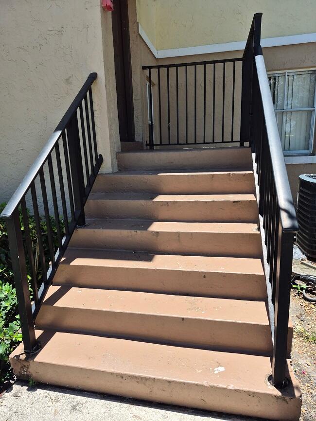 Exterior concrete stairs with black metal railings lead up to a building entrance — 2823 N Course Drive # 205, Pompano Beach FL 33069, POMPANO BEACH, FL