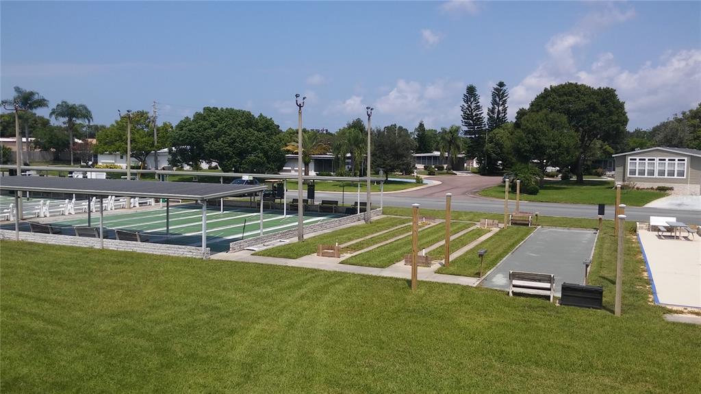 An outdoor recreational area features shuffleboard courts and a covered pavilion on a grassy lawn — 57 HARBOR WAY UNIT 24, PALM HARBOR, FL