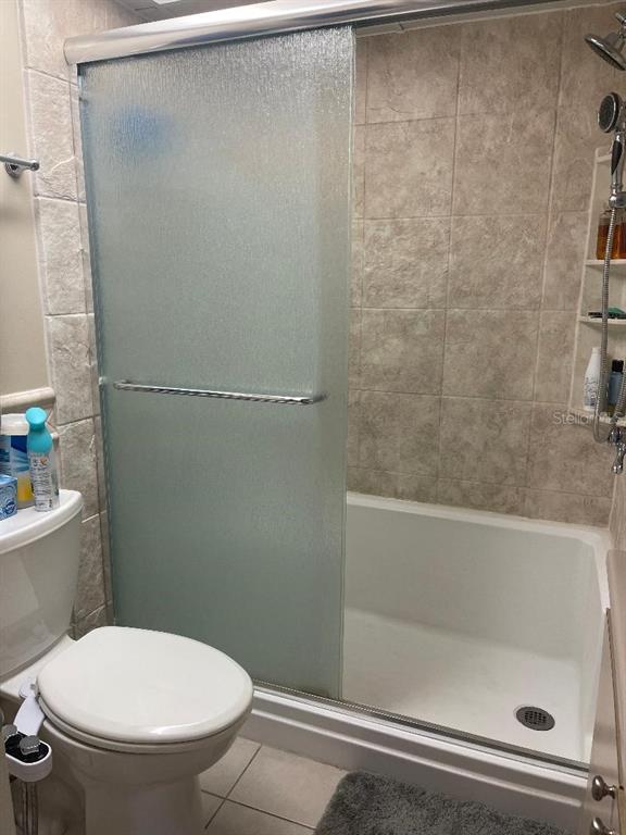 A bathroom features a toilet with a bidet attachment next to a tiled walk-in shower — 57 HARBOR WAY UNIT 24, PALM HARBOR, FL