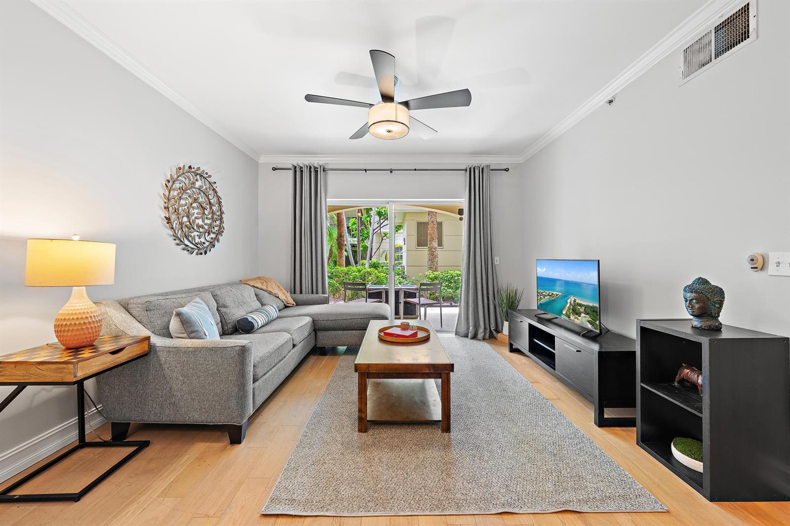 A living room features a gray sectional sofa, a coffee table, and a sliding glass door — 4117 Tuscany Way # 4117, Boynton Beach FL 33435, BOYNTON BEACH, FL