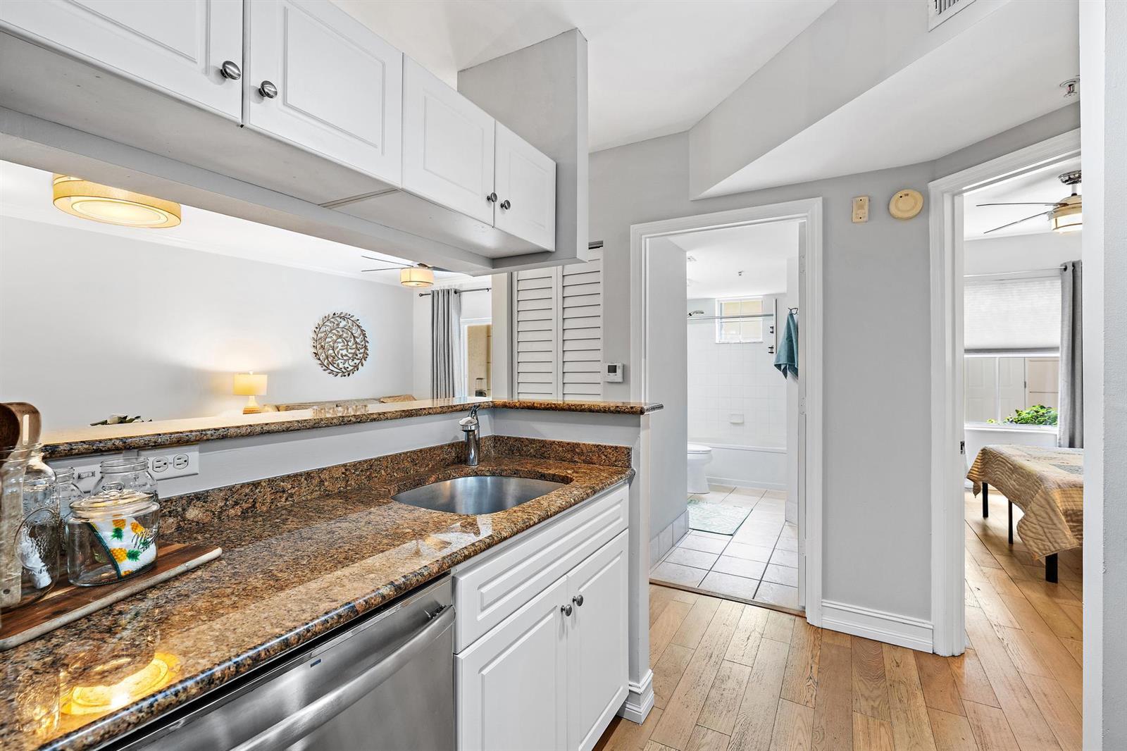 A kitchen with granite countertops and white cabinets overlooks a living area and hallway — 4117 Tuscany Way # 4117, Boynton Beach FL 33435, BOYNTON BEACH, FL